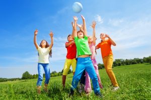 Happy kids catching ball in air outside